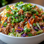 Egg roll in a bowl with coleslaw mix in a bowl garnished with green onions and parsley